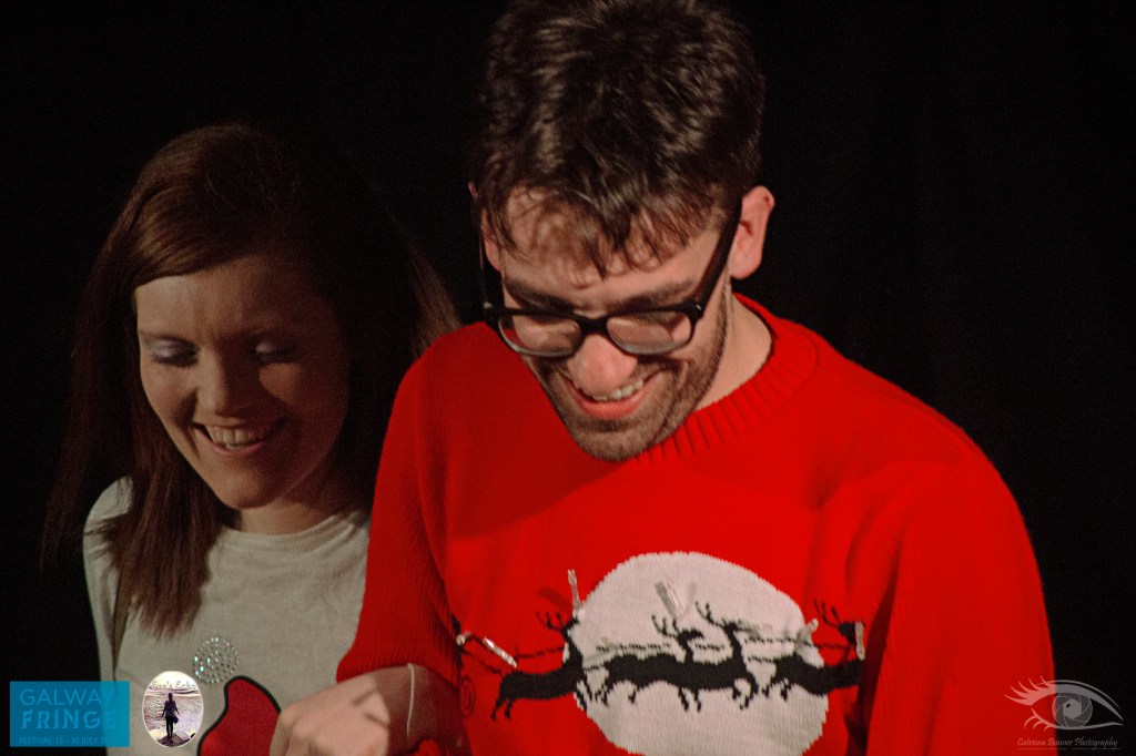 Two actors smile wearing Christmas jumpers